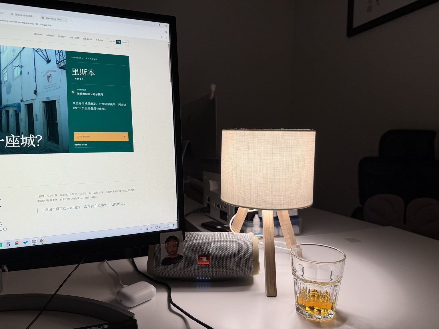 夜晚办公桌上的三脚台灯亮着暖光,旁边是电脑、音箱和一只酒杯