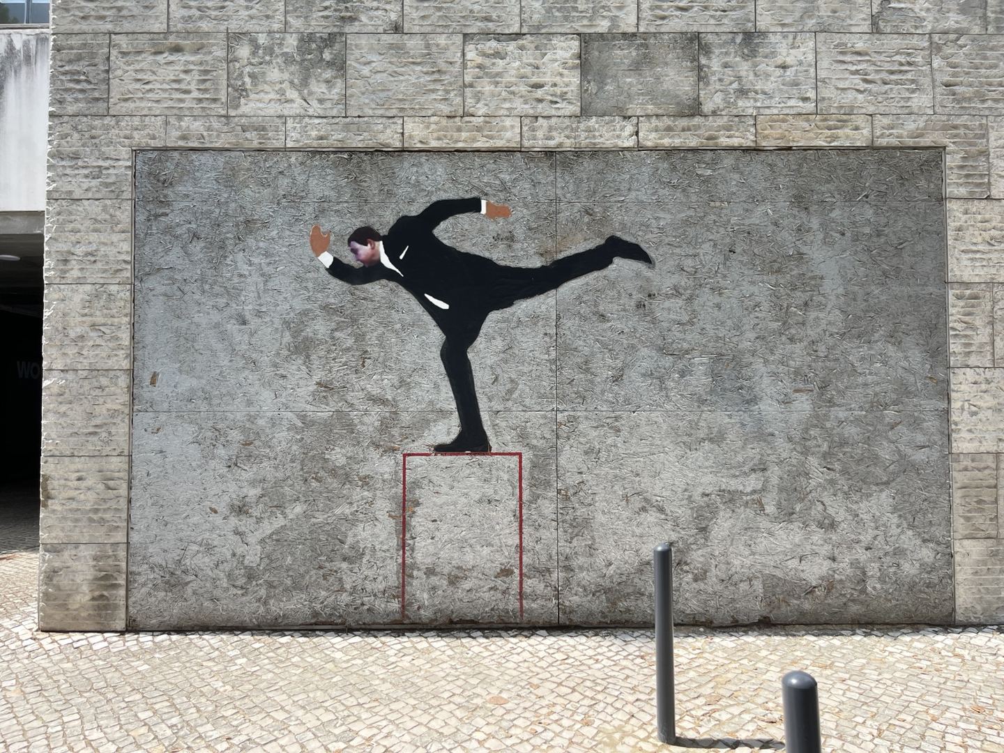 Arte urbana a sul da Expo: um homem de fato preto equilibra-se num só pé sobre uma plataforma desenhada a vermelho