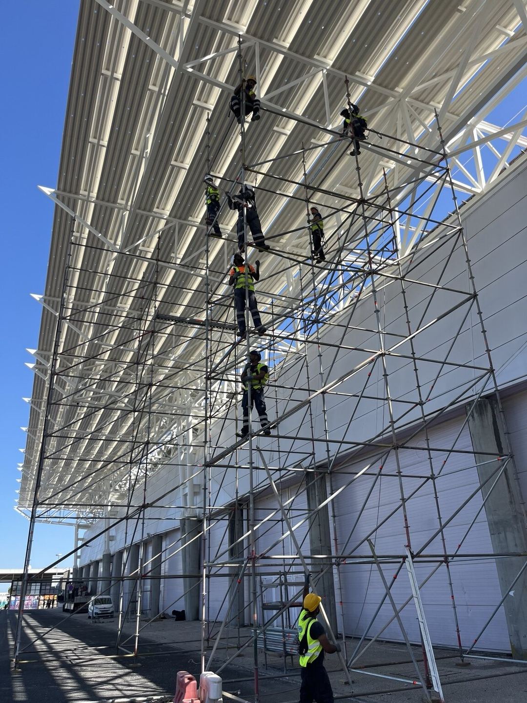 里斯本国际展览中心外墙的脚手架上,多名工人在白色展翼下进行刷新工程