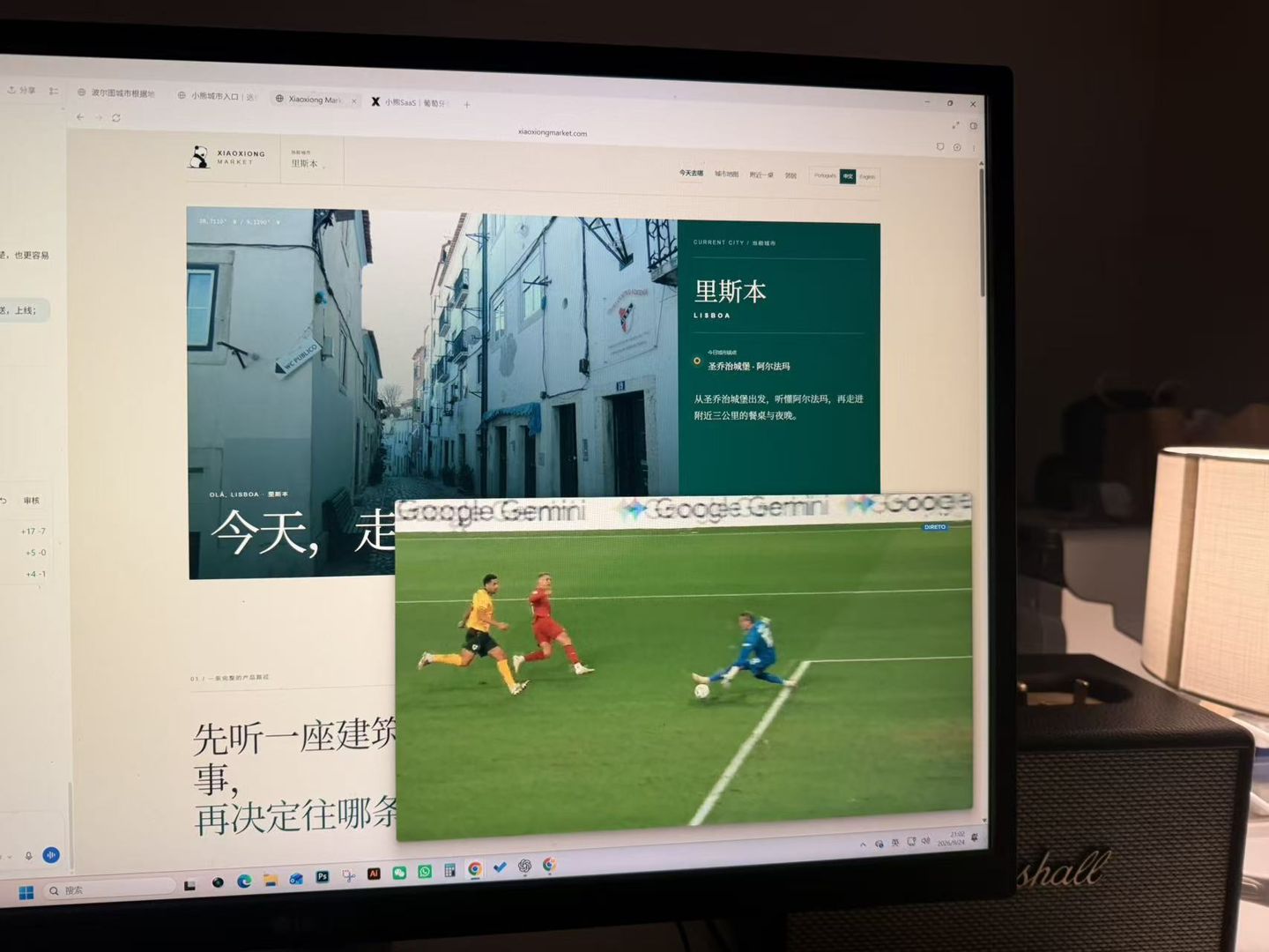 办公室电脑上,小熊里斯本页面与葡萄牙对威尔士的比赛画面同时打开,旁边亮着台灯